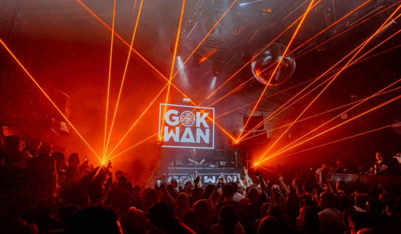 Photo of the crowd and the stage at a Gok Wan event. You can see a dancing crowd and lazers.